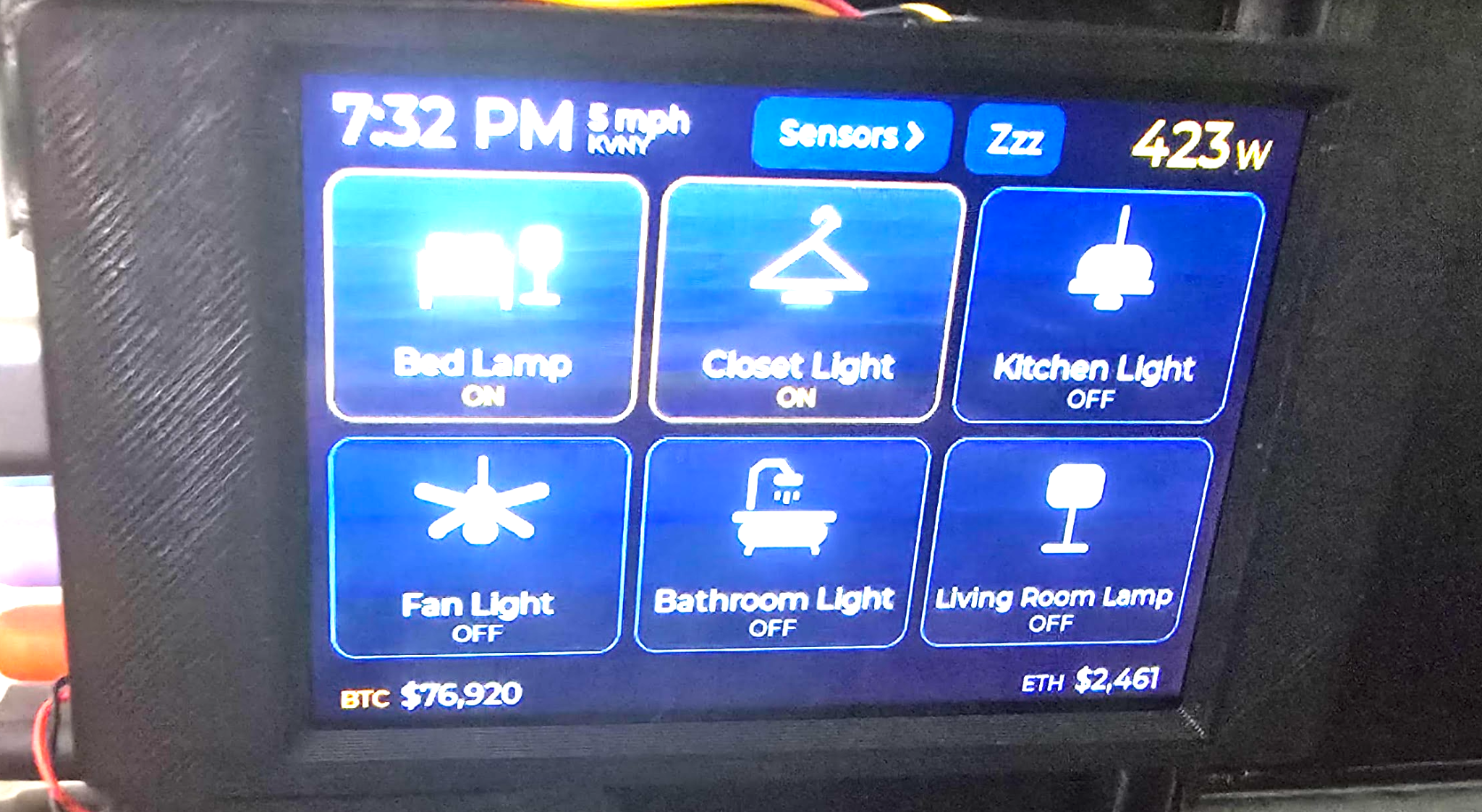 My ESP32 panel in its black enclosure, showing six room lighting controls, KVNY wind, a wattage display, and BTC and ETH values.
